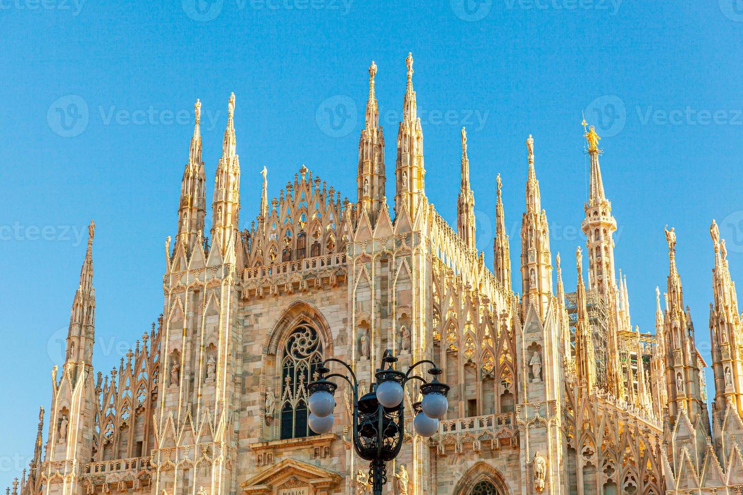 Famous church Milan Cathedral Duomo di Milano with Gothic spires and white marble statues. Top tourist attraction on piazza in Milan Lombardia Italy. Wide angle view of old Gothic architecture and art photo