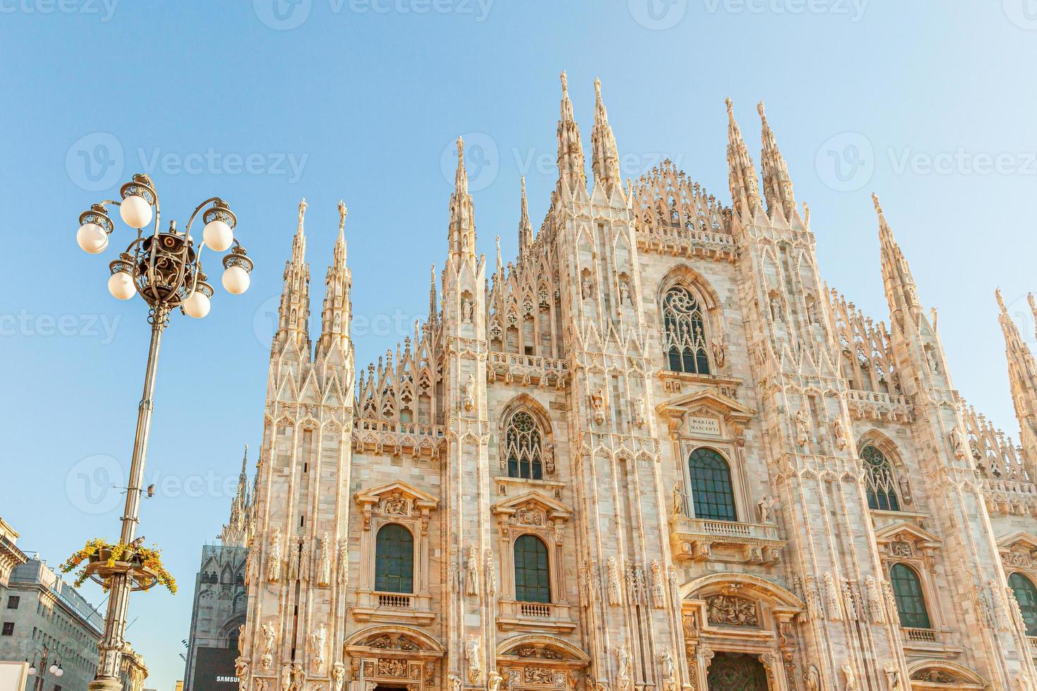 Famous church Milan Cathedral Duomo di Milano with Gothic spires and white marble statues. Top tourist attraction on piazza in Milan Lombardia Italy. Wide angle view of old Gothic architecture and art photo