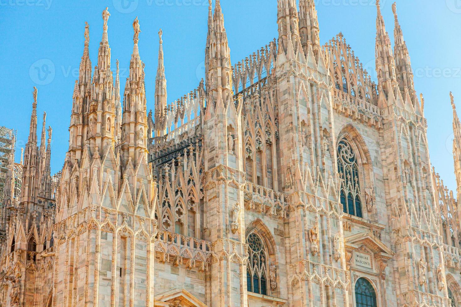 Famous church Milan Cathedral Duomo di Milano with Gothic spires and white marble statues. Top tourist attraction on piazza in Milan Lombardia Italy. Wide angle view of old Gothic architecture and art photo