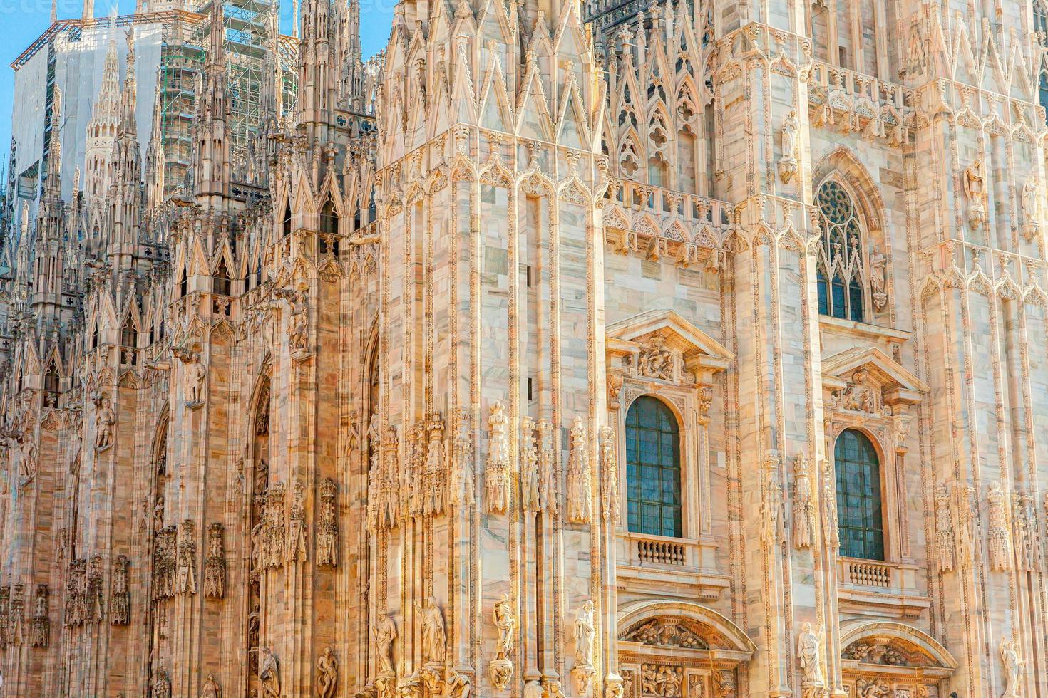 Famous church Milan Cathedral Duomo di Milano with Gothic spires and white marble statues. Top tourist attraction on piazza in Milan Lombardia Italy. Wide angle view of old Gothic architecture and art photo