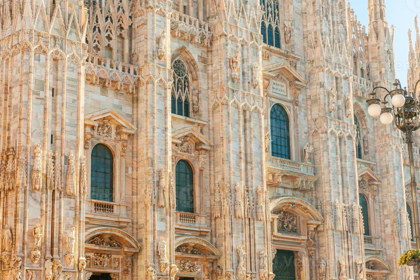 Famous church Milan Cathedral Duomo di Milano with Gothic spires and white marble statues. Top tourist attraction on piazza in Milan Lombardia Italy. Wide angle view of old Gothic architecture and art photo
