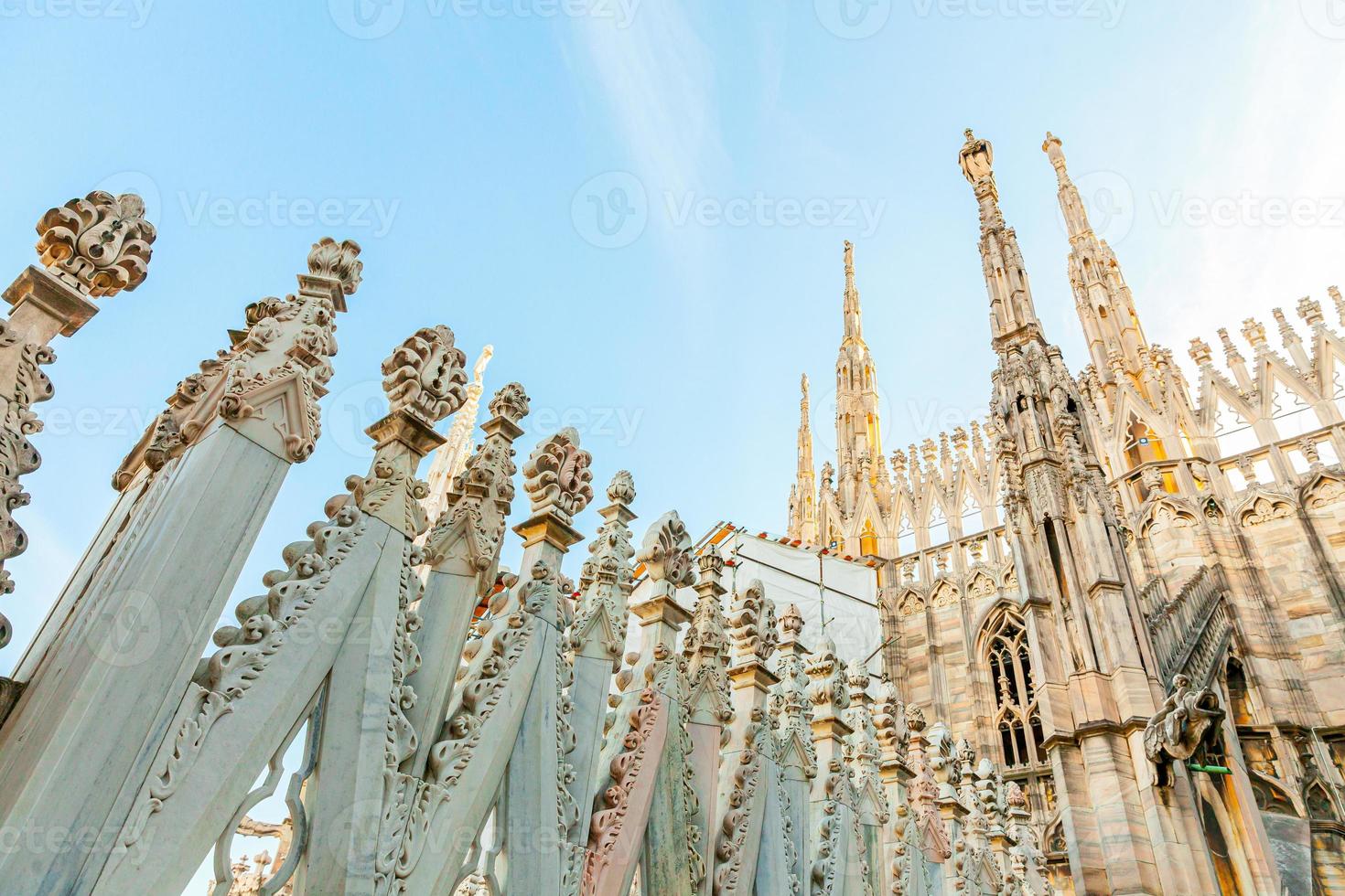 Roof of Milan Cathedral Duomo di Milano with Gothic spires and white marble statues. Top tourist attraction on piazza in Milan, Lombardia, Italy. Wide angle view of old Gothic architecture and art. photo
