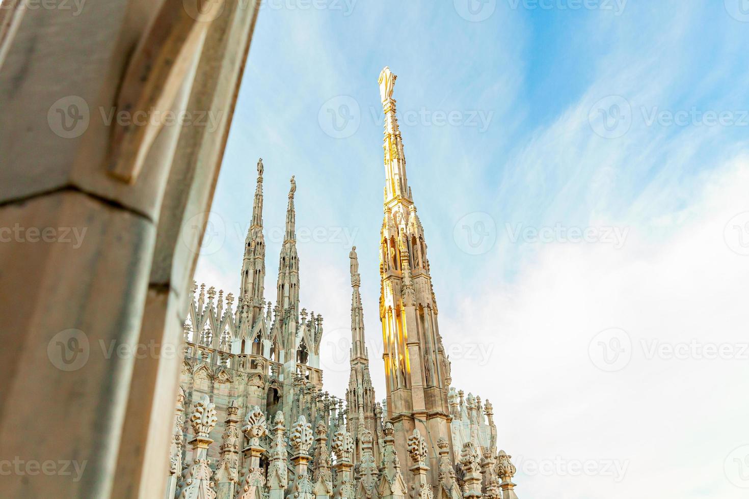 Roof of Milan Cathedral Duomo di Milano with Gothic spires and white marble statues. Top tourist attraction on piazza in Milan, Lombardia, Italy. Wide angle view of old Gothic architecture and art. photo
