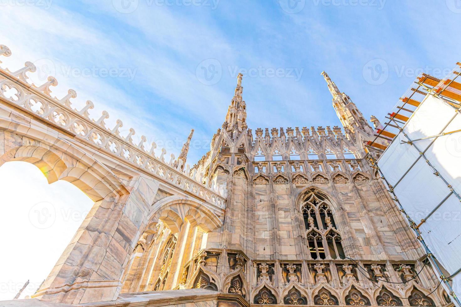 Roof of Milan Cathedral Duomo di Milano with Gothic spires and white marble statues. Top tourist attraction on piazza in Milan, Lombardia, Italy. Wide angle view of old Gothic architecture and art. photo