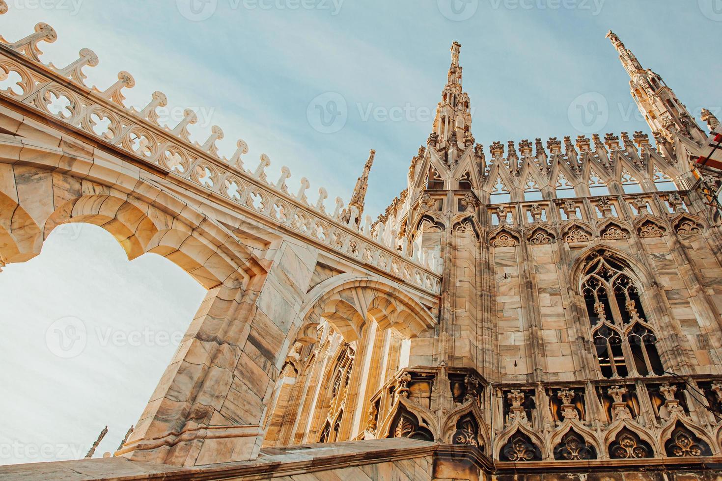 Roof of Milan Cathedral Duomo di Milano with Gothic spires and white marble statues. Top tourist attraction on piazza in Milan, Lombardia, Italy. Wide angle view of old Gothic architecture and art. photo