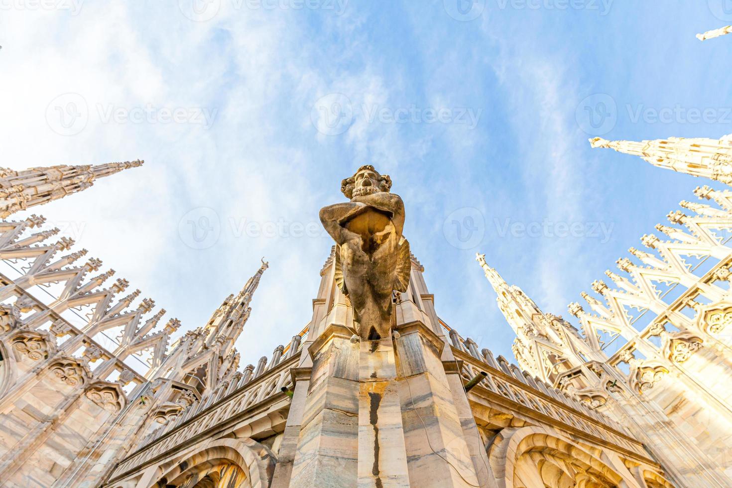 Roof of Milan Cathedral Duomo di Milano with Gothic spires and white marble statues. Top tourist attraction on piazza in Milan, Lombardia, Italy. Wide angle view of old Gothic architecture and art. photo