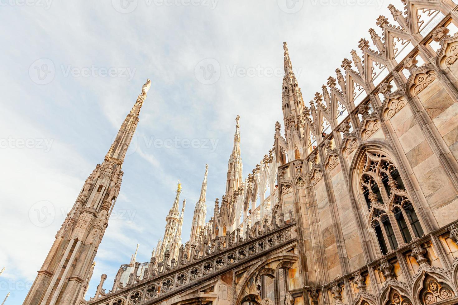 Roof of Milan Cathedral Duomo di Milano with Gothic spires and white marble statues. Top tourist attraction on piazza in Milan, Lombardia, Italy. Wide angle view of old Gothic architecture and art. photo