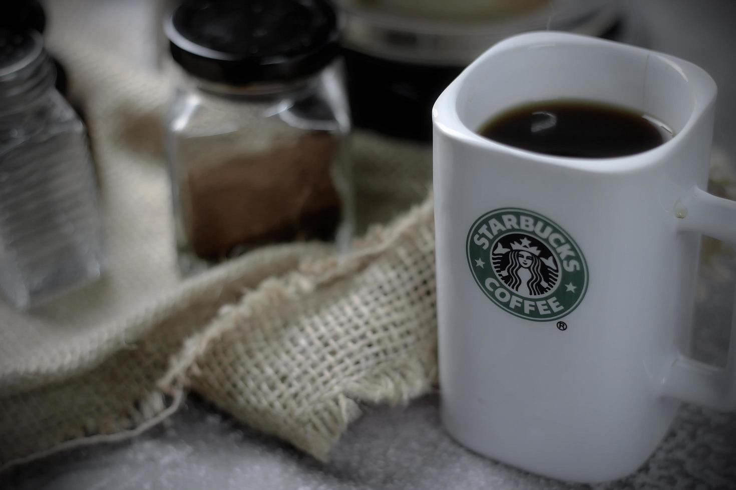 WASHINGTON - USA September, 26 2022  Starbucks coffee mug on gray table with coffee bottle and coffee grinder. photo