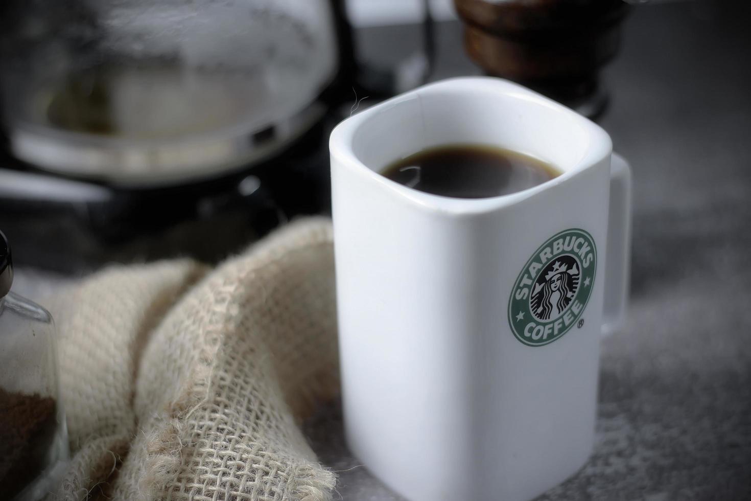 WASHINGTON - USA September, 26 2022  Starbucks coffee mug on gray table with coffee bottle and coffee grinder. photo