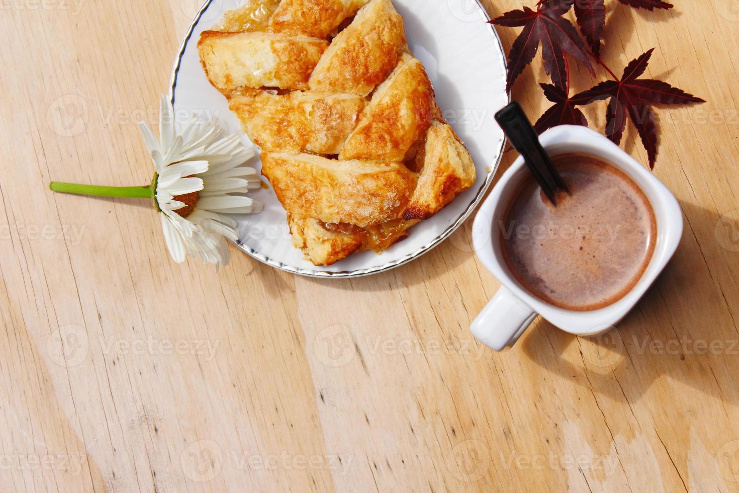 Coffee mugs and pastries served on a wooden table with crimson Japanese maple leaves and white daisies. Top view photo. photo