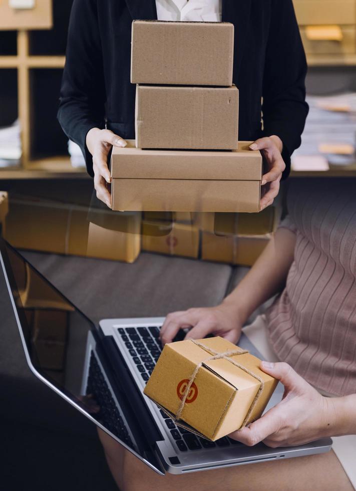 Startup SME small business entrepreneur of freelance Asian woman using a laptop with box Cheerful success Asian woman her hand lifts up online marketing packaging box and delivery SME idea concept photo