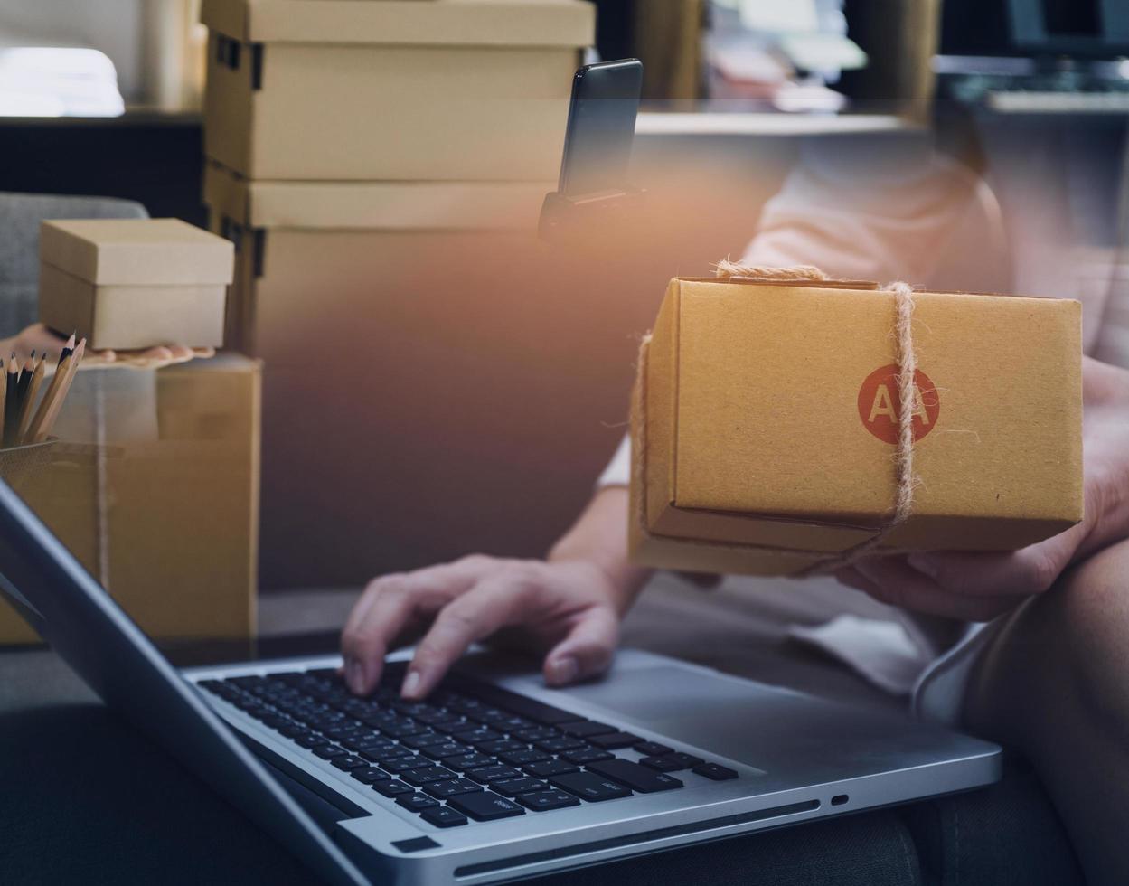 Startup SME small business entrepreneur of freelance Asian woman using a laptop with box Cheerful success Asian woman her hand lifts up online marketing packaging box and delivery SME idea concept photo