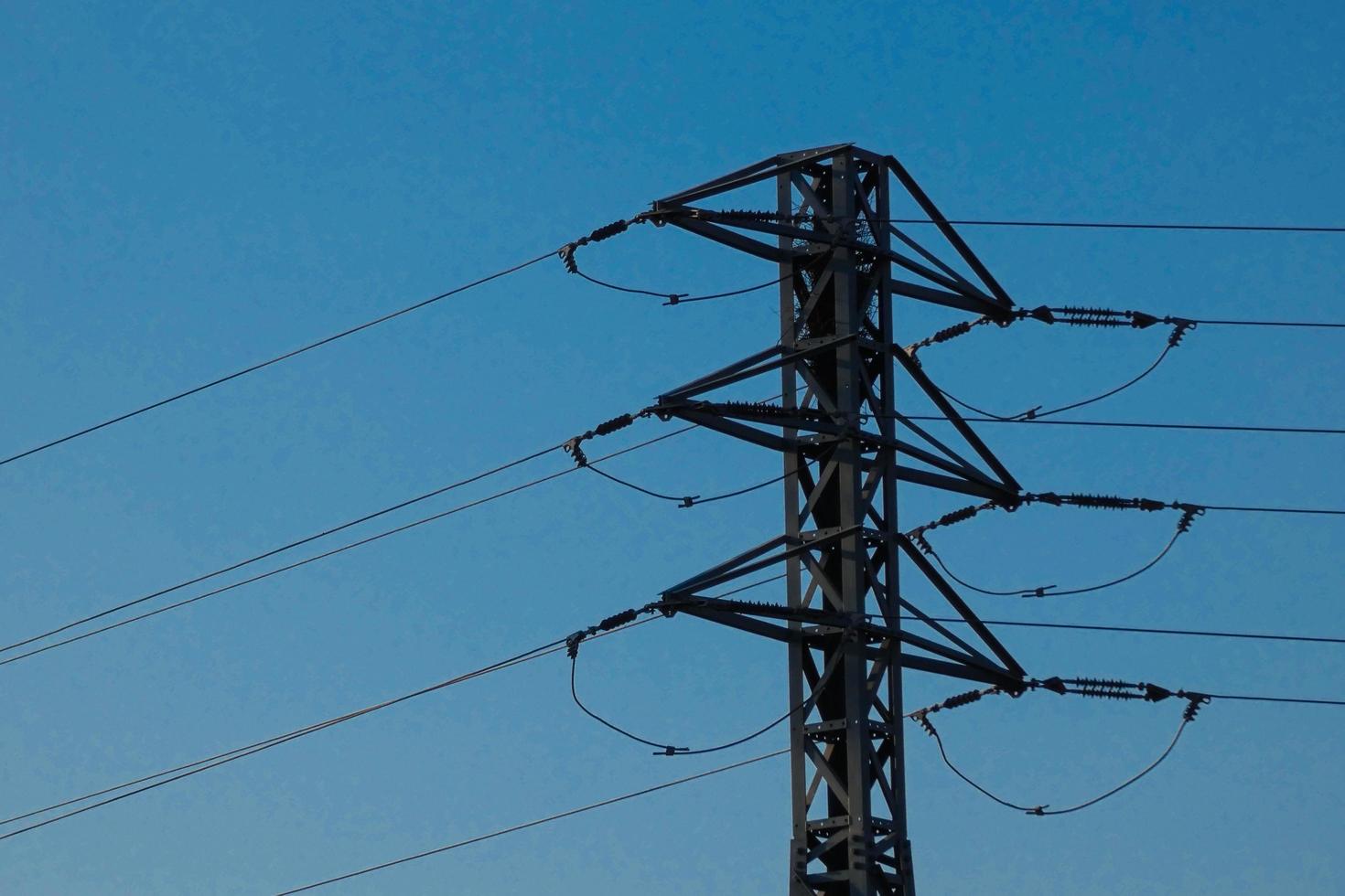 torres eléctricas de silueta que soportan cables de cobre para transportar energía eléctrica foto