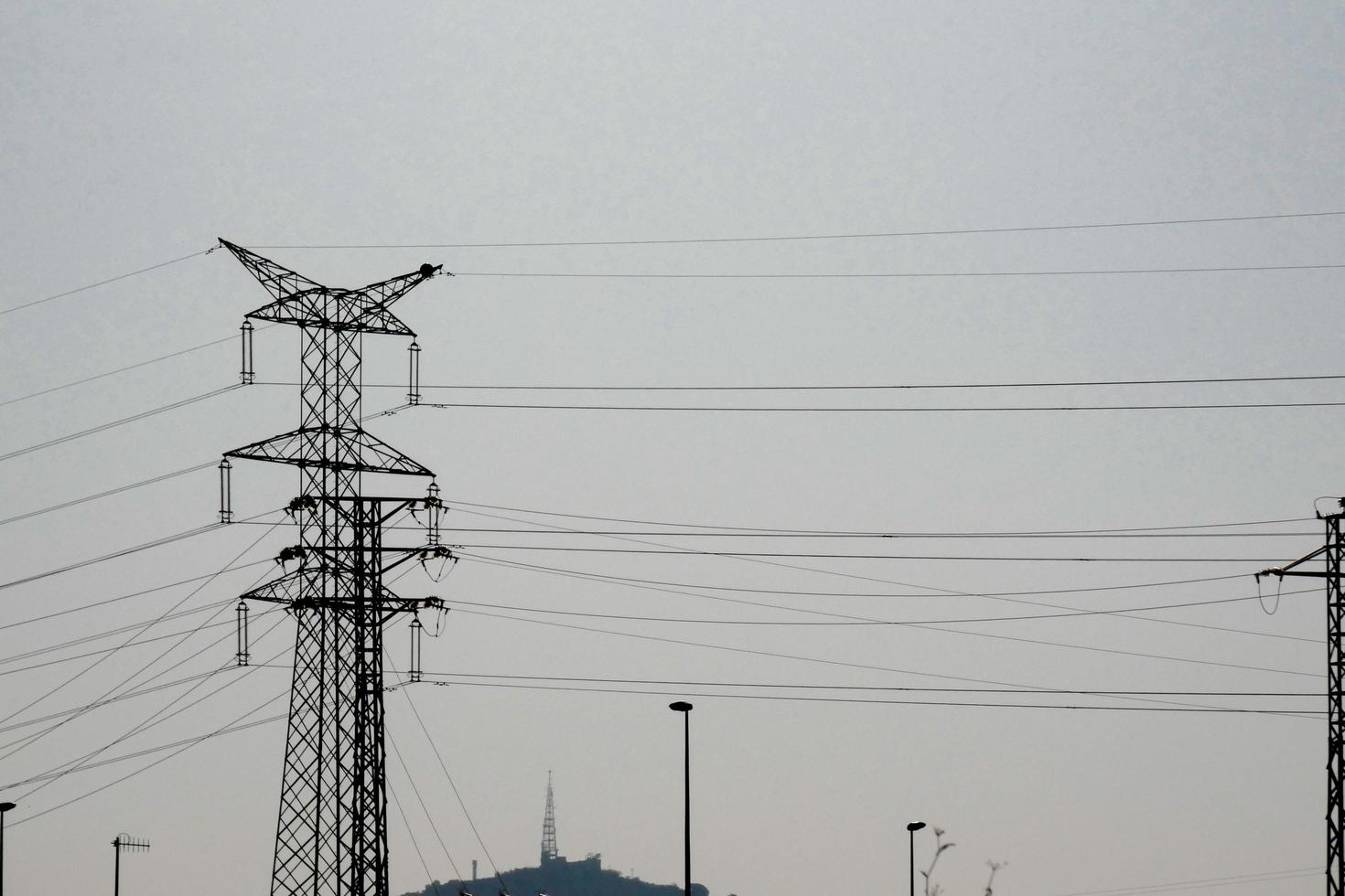 silhouette electric towers supporting copper cables to transport electric energy photo