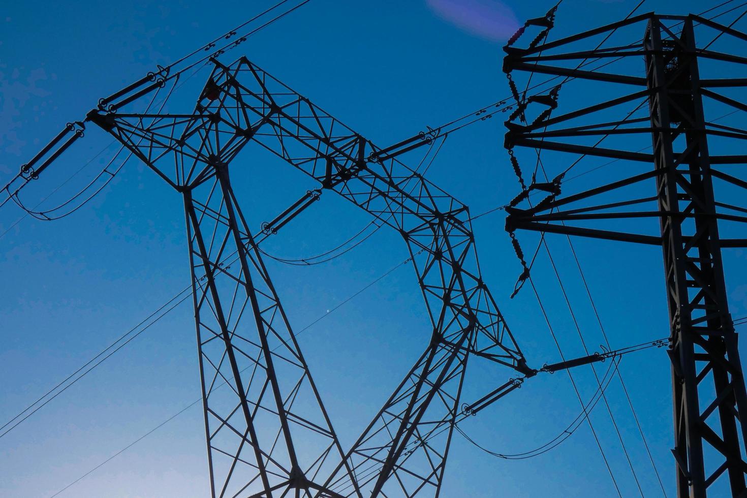 silhouette electric towers supporting copper cables to transport electric energy photo