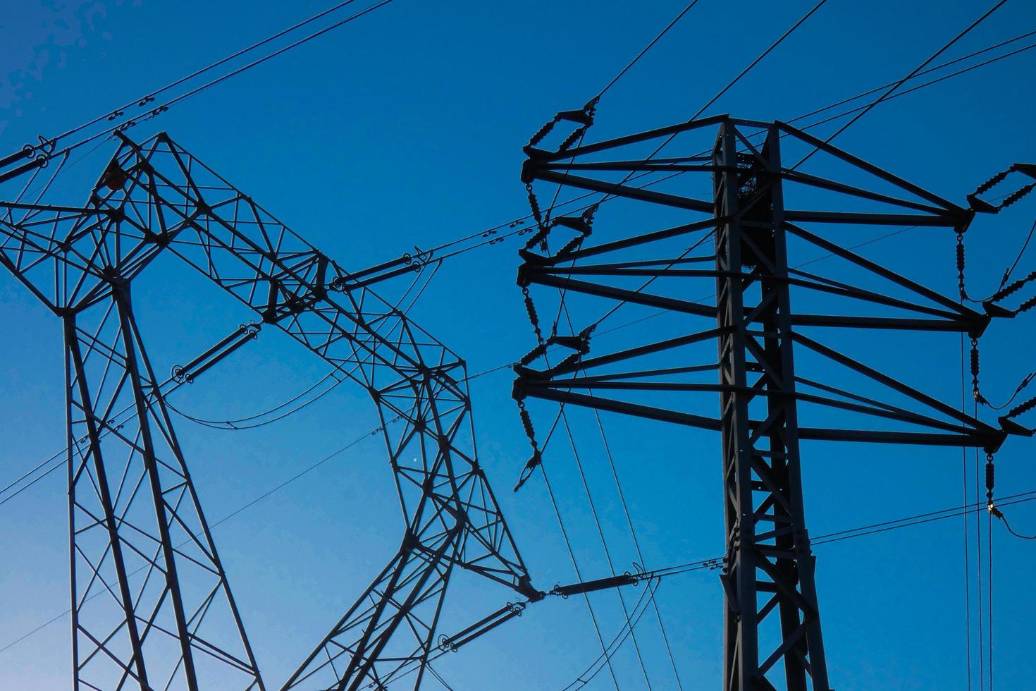 silhouette electric towers supporting copper cables to transport electric energy photo