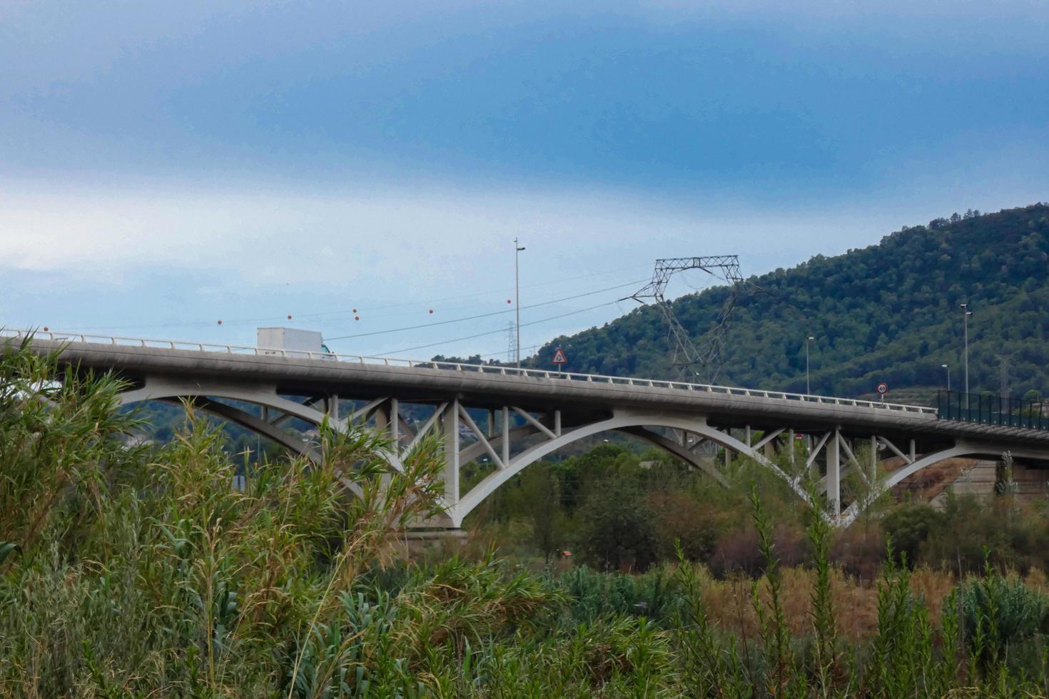 moderno puente sobre un río por el que pasan grandes vehículos y turistas. foto