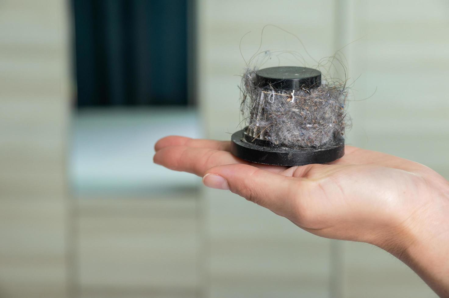 Housekeeper holding a vacuum dust filter after cleaning house. A purpose of this filter is to collect the dust that passes through the suction nozzle from the carpet or floor. photo