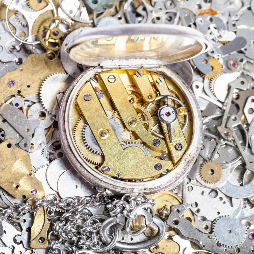open retro pocket watch on heap of spare parts photo