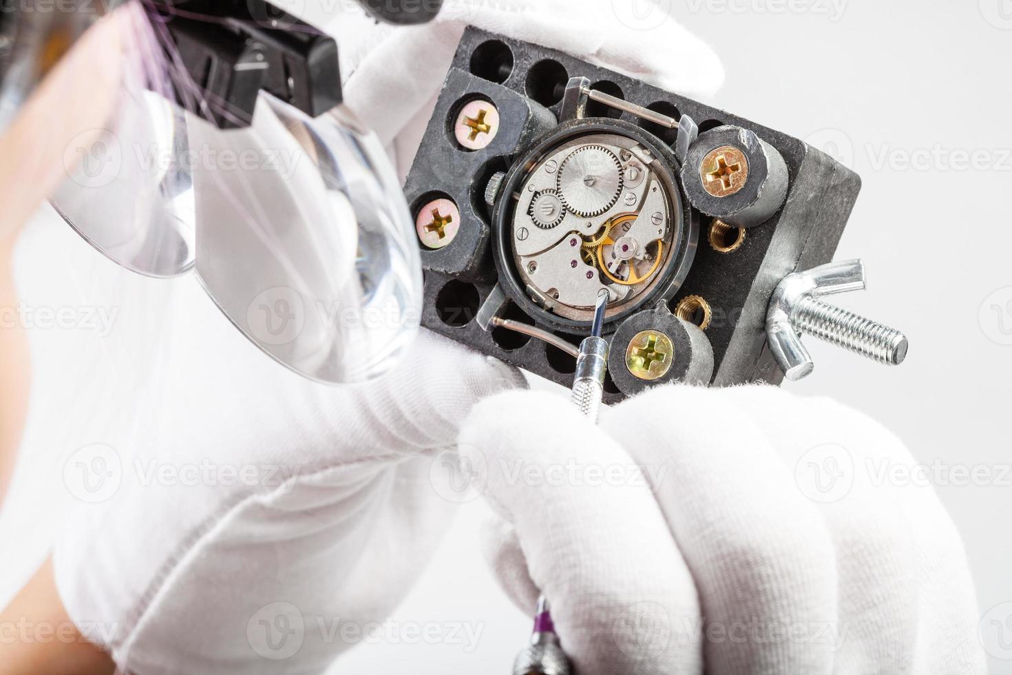 watchmaker in magnifying glasses repairs old watch photo