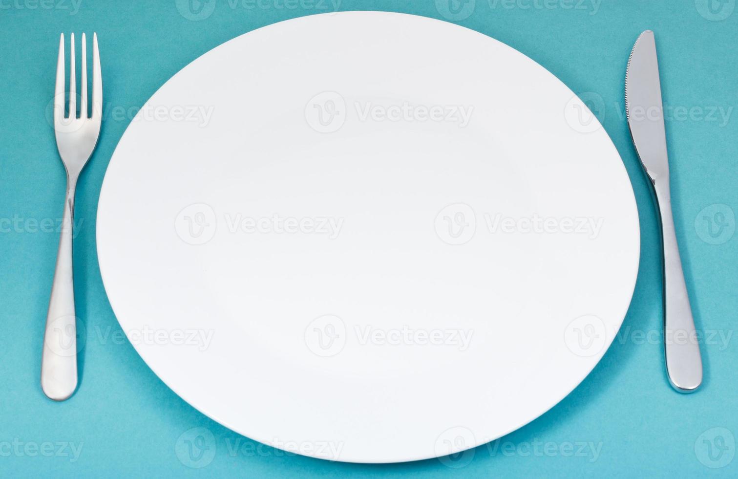 white porcelain plate with fork and knife on green photo