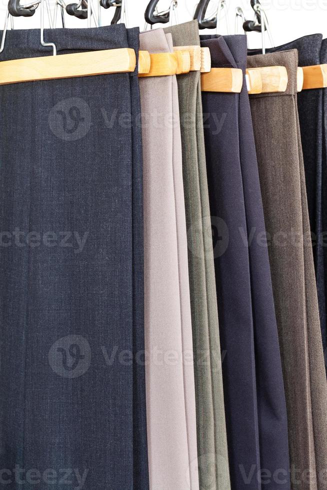 various woolen trousers on hangers photo