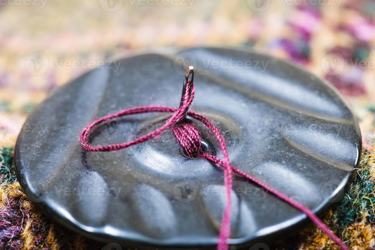 attaching of button to woolen dress by needle photo