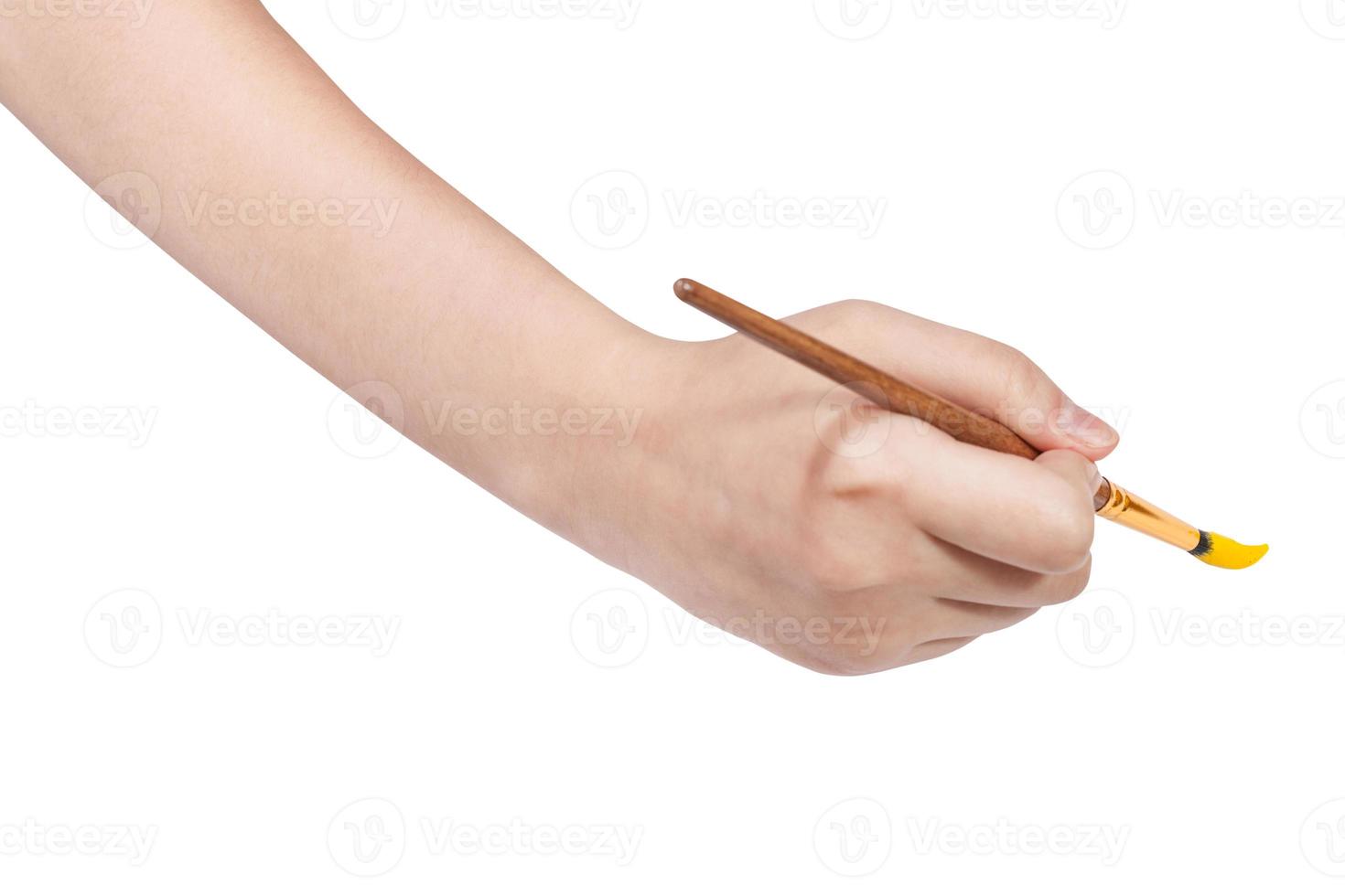 hand with artistic paintbrush paints in yellow photo