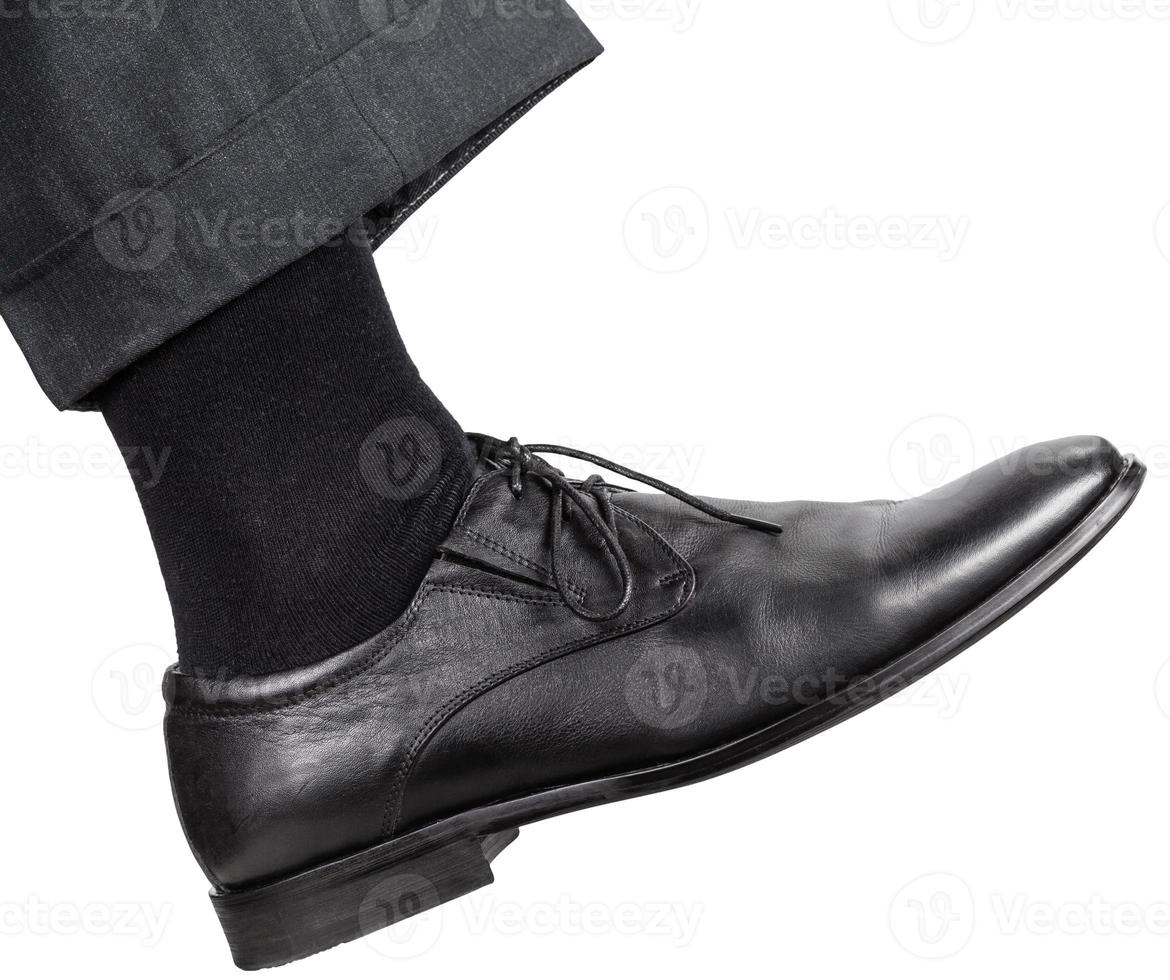 male right leg in black shoe takes a step photo