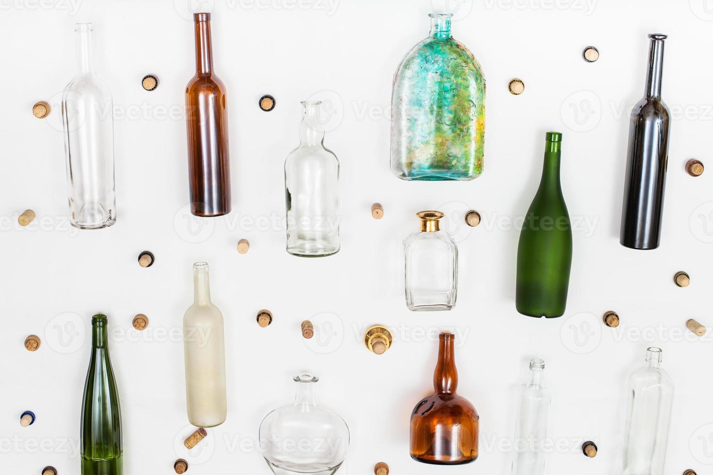 empty glass bottles and corks arranged on white photo