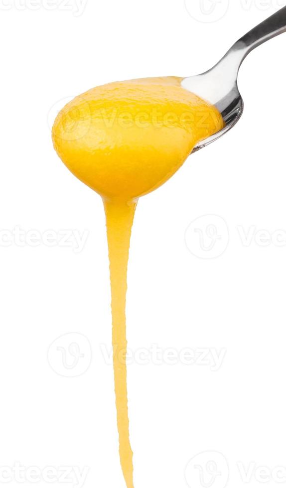 yellow honey flowing down from spoon close up photo