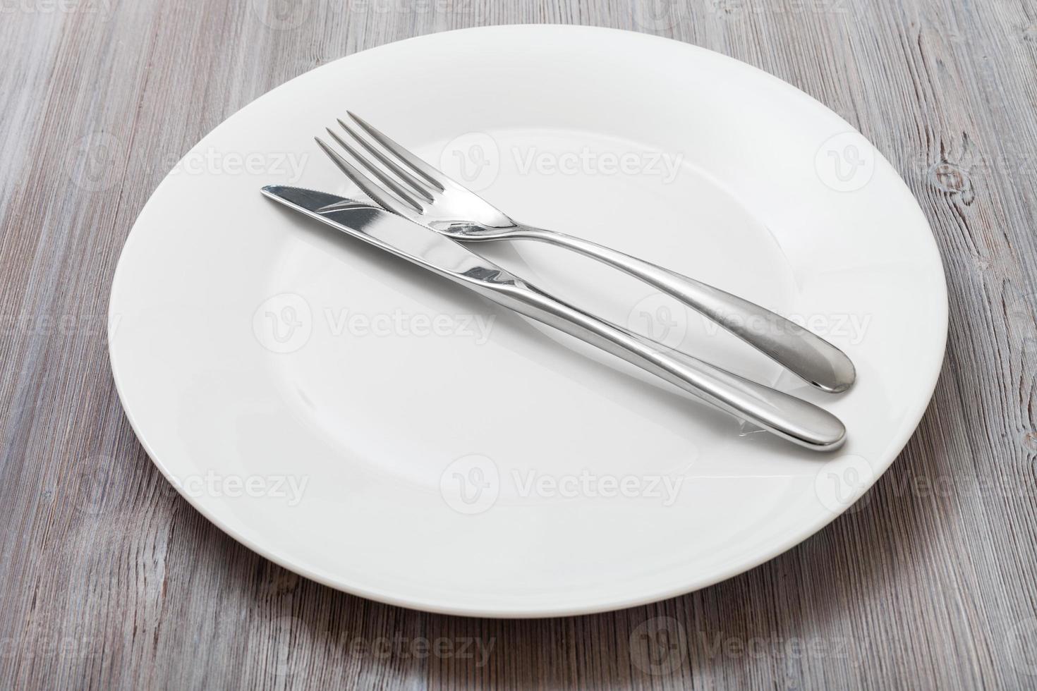 white plate with parallel knife, spoon on gray photo