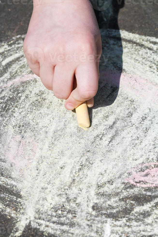 girl paints with colored chalk on asphalt photo