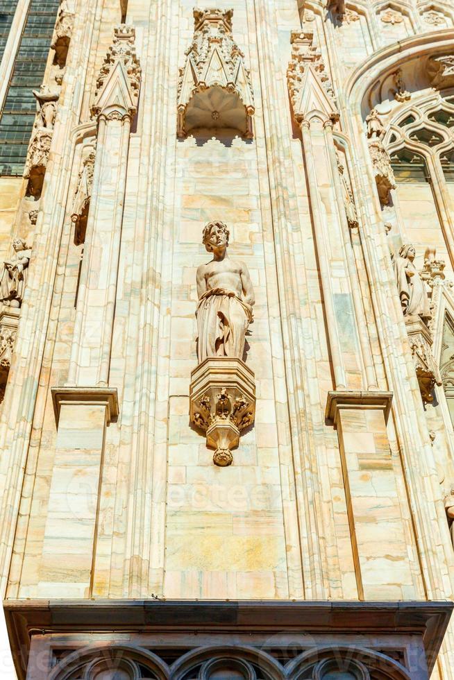 Facade of Milan Cathedral Duomo di Milano with Gothic spires and white marble statues. Top tourist attraction on piazza in Milan, Lombardia, Italy. Wide angle view of old Gothic architecture and art. photo