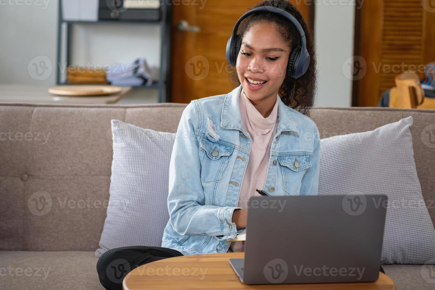 mujer africana, estadounidense, usando computadora portátil y usando auriculares para aprender en línea. foto