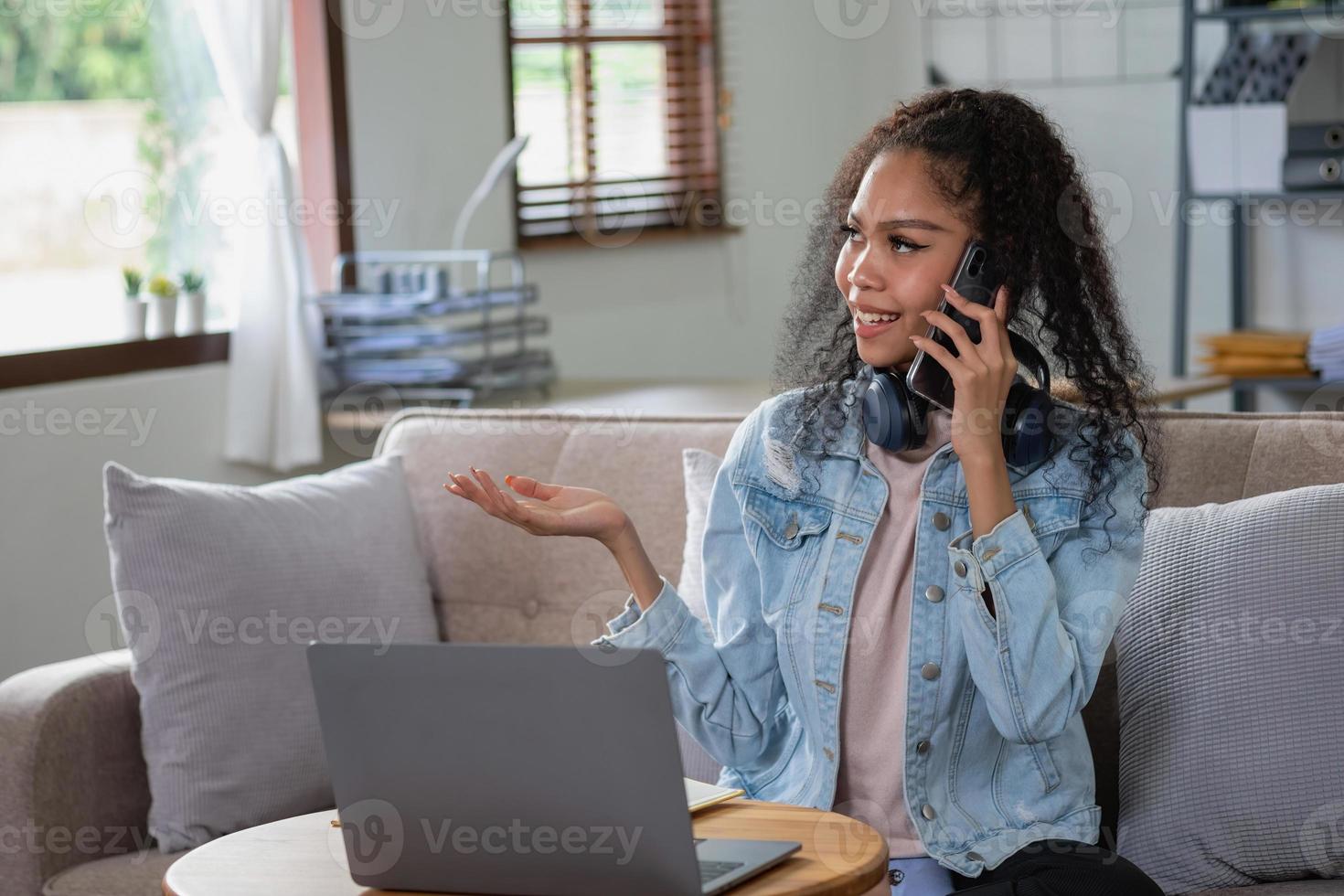 African woman, American, using laptop computer and wearing headphones for online learning. photo