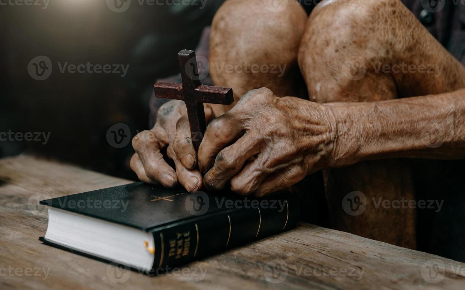 anciano sentado y estudiando las escrituras. la cruz de madera en las manos. conceptos de educación cristiana las sagradas escrituras abiertas foto