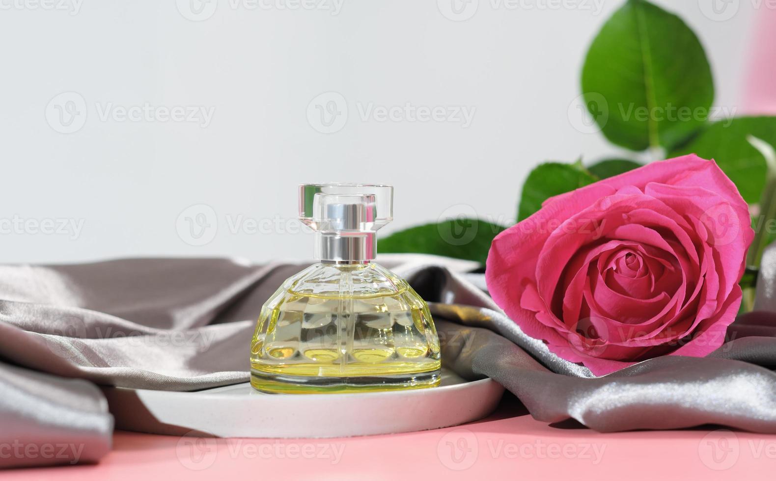 perfume bottle, floral light fragrance for woman. pink rose, aroma spray next to silk bedding sheet photo