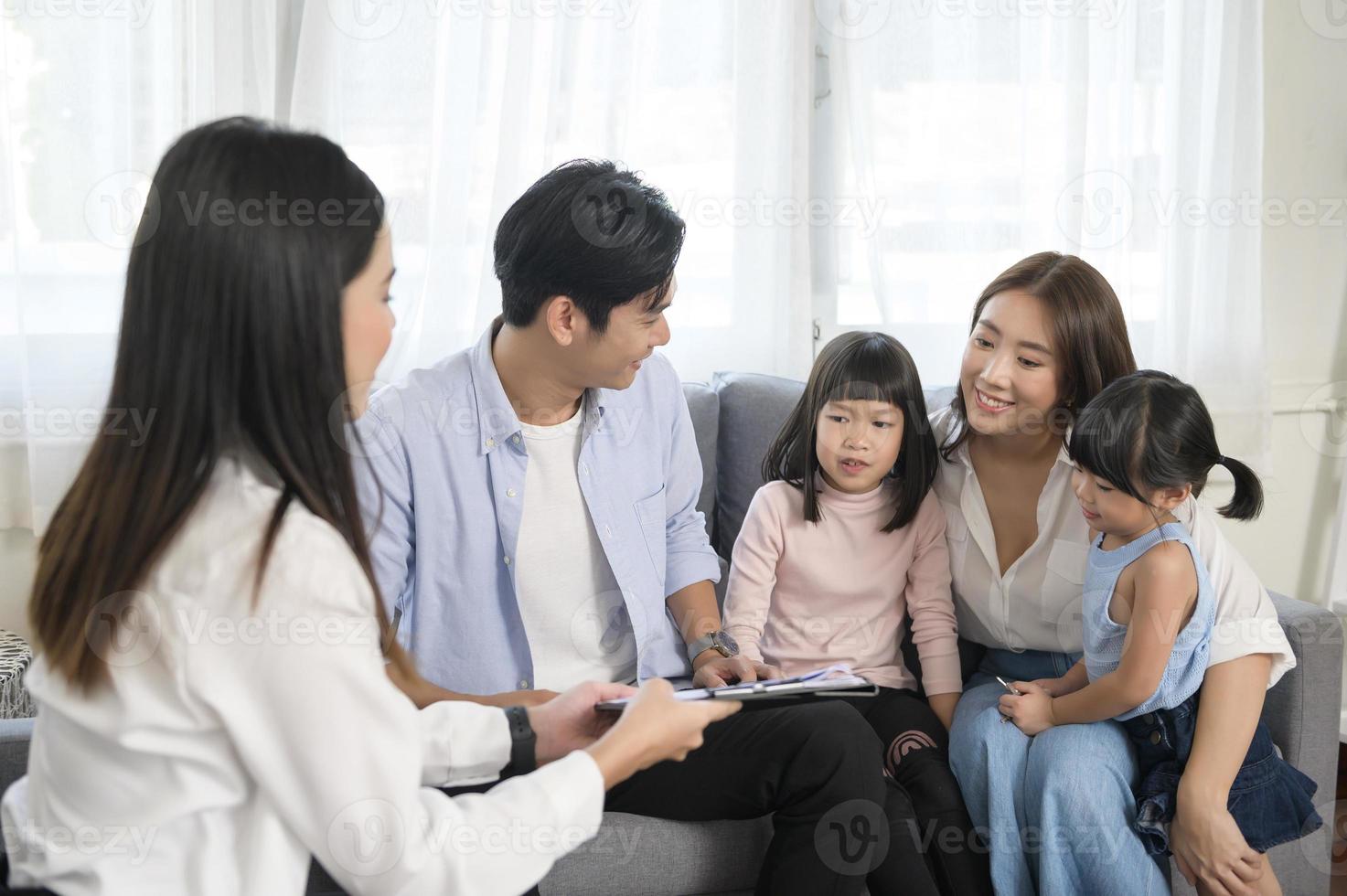 Asian family meeting with female real estate agent or insurance consultant offering promotions , Mortgage, loan, property and medical health insurance concept. photo