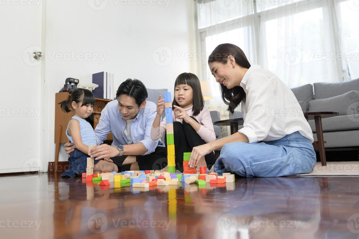 Asian family with children playing and building tower of colorful wooden toy blocks in living room at home, Educational game. photo