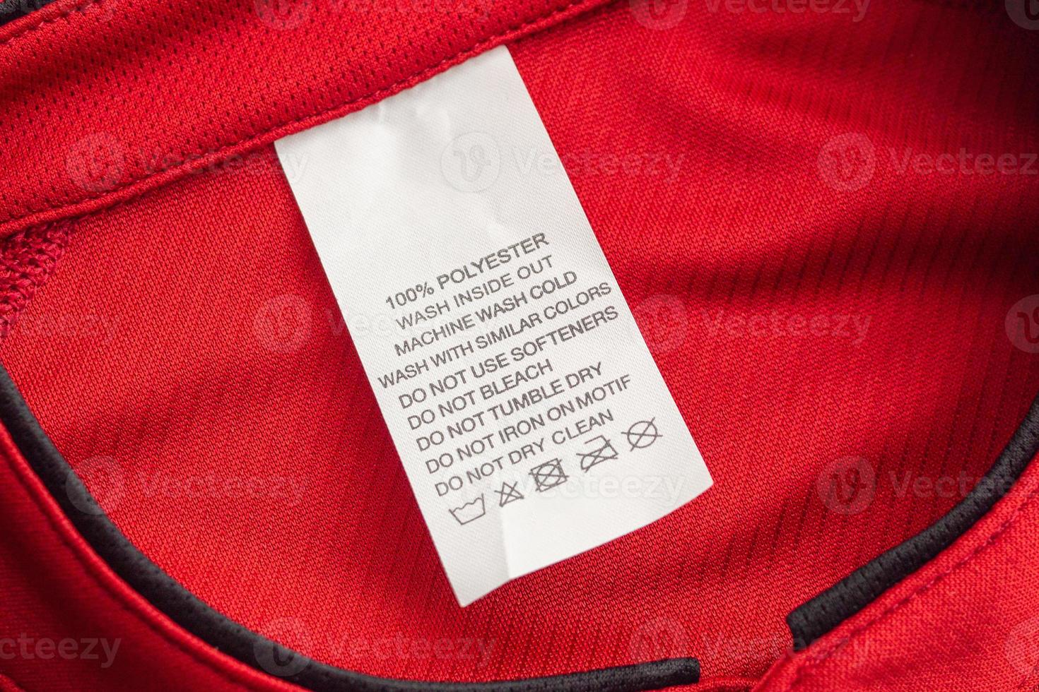 White laundry care washing instructions clothes label on red jersey polyester sport shirt photo