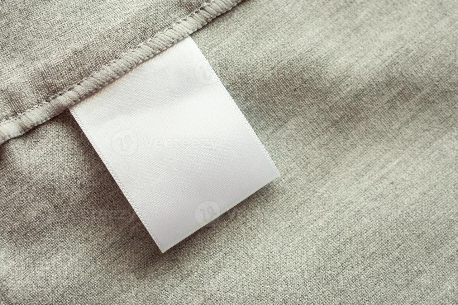 White blank laundry care clothing label on gray fabric texture background photo