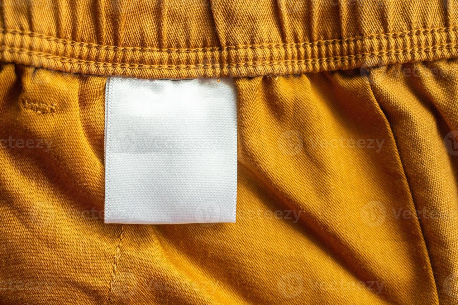 White blank clothing tag label on brown cotton shorts fabric texture background photo