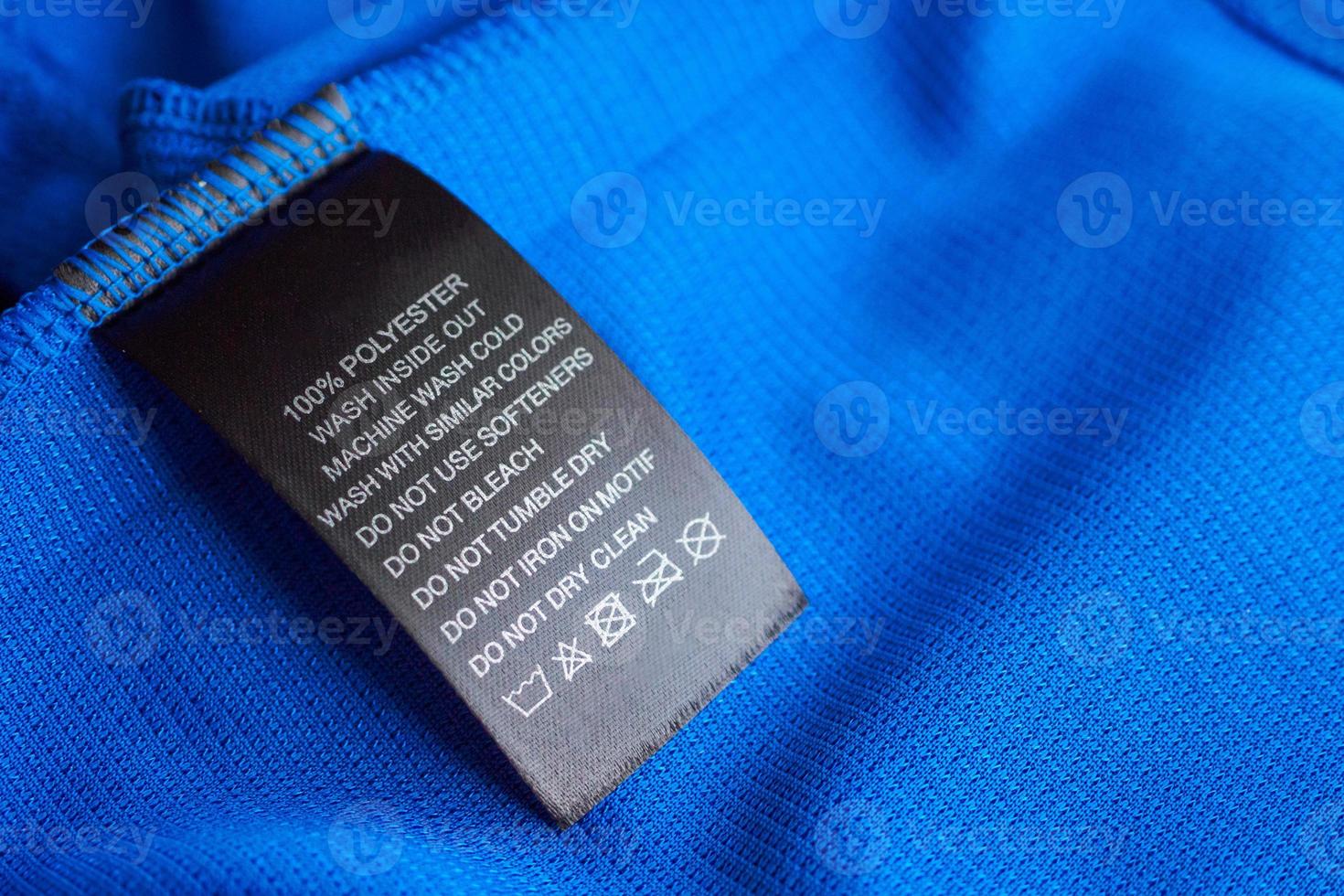 Black laundry care washing instructions clothes label on blue jersey polyester sport shirt photo