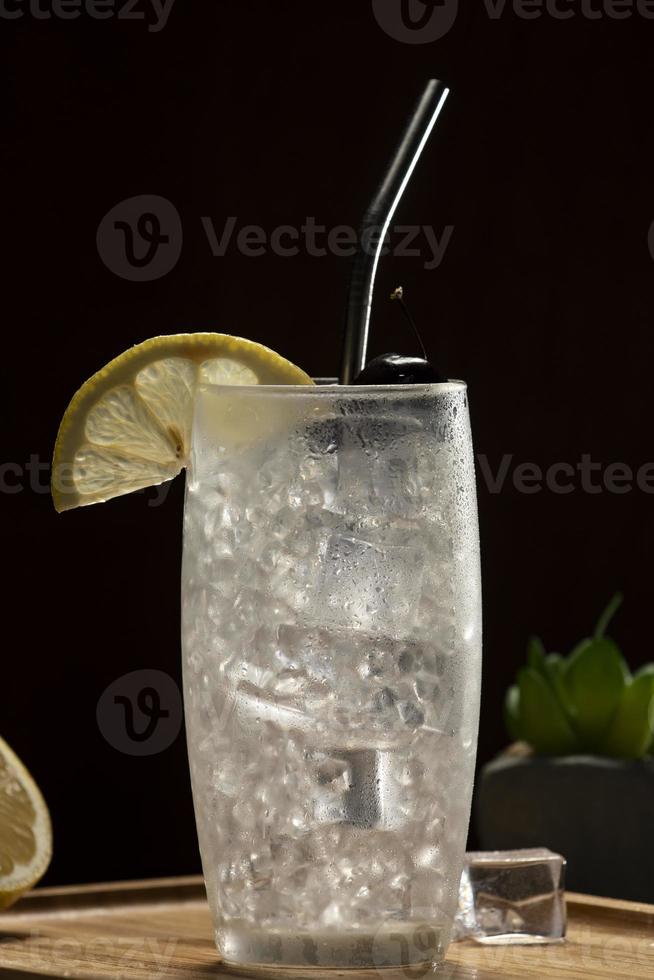 cóctel de tom collins en un fondo negro, paja de metal ecológica foto