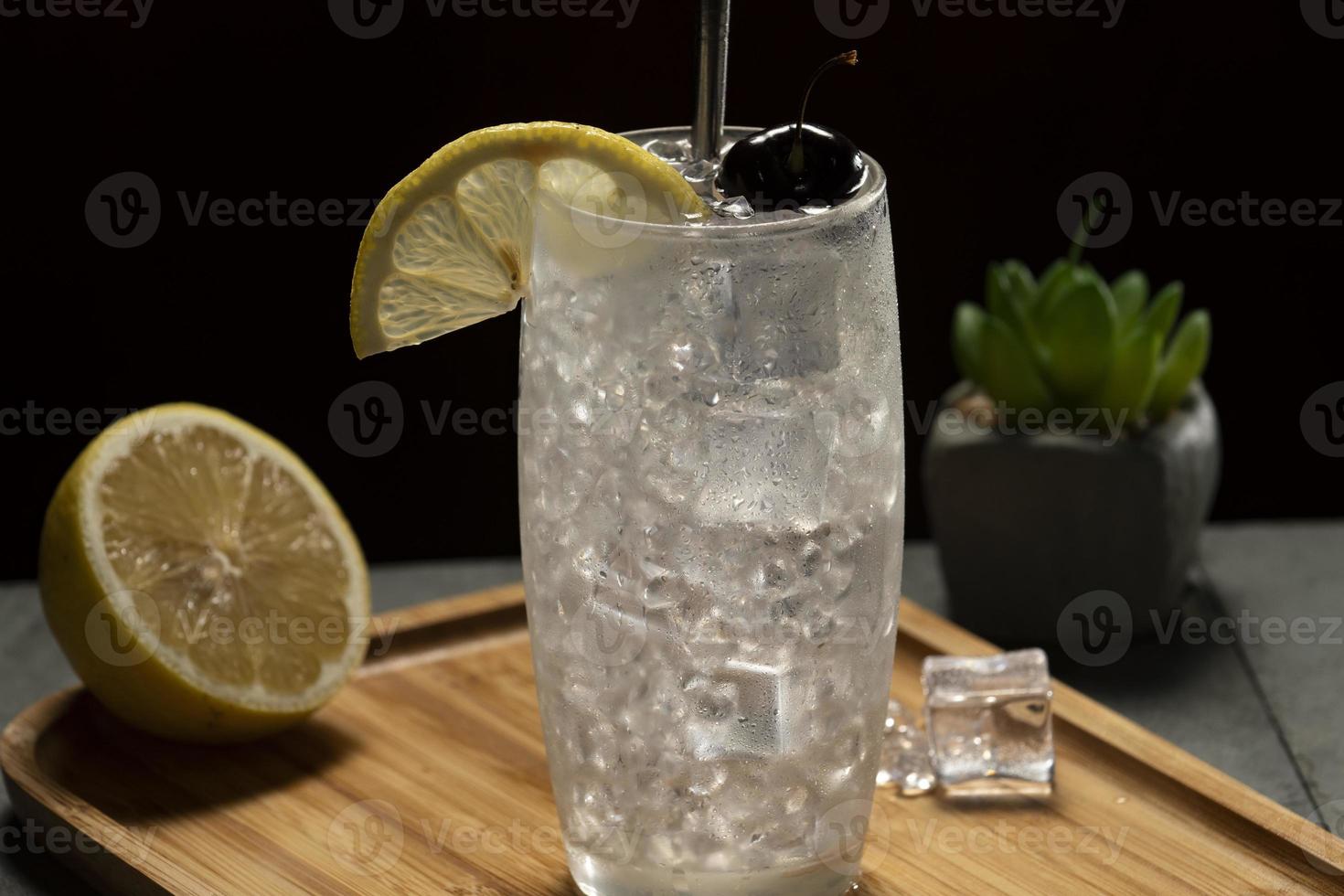 Tom Collins cocktail in a black background, eco-friendly metal straw photo