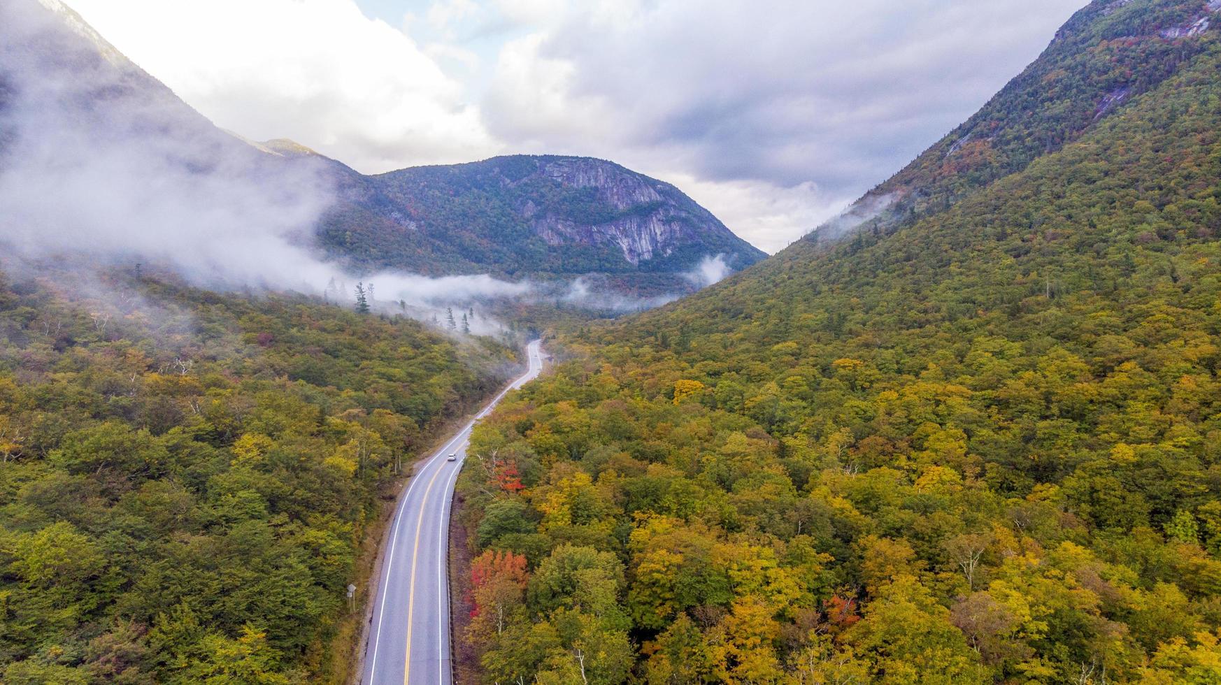 camino ventoso que atraviesa el bosque entre montañas en otoño foto