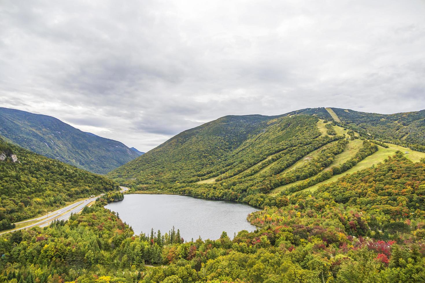 Mountain with a ski resort in front of a pond in the fall photo