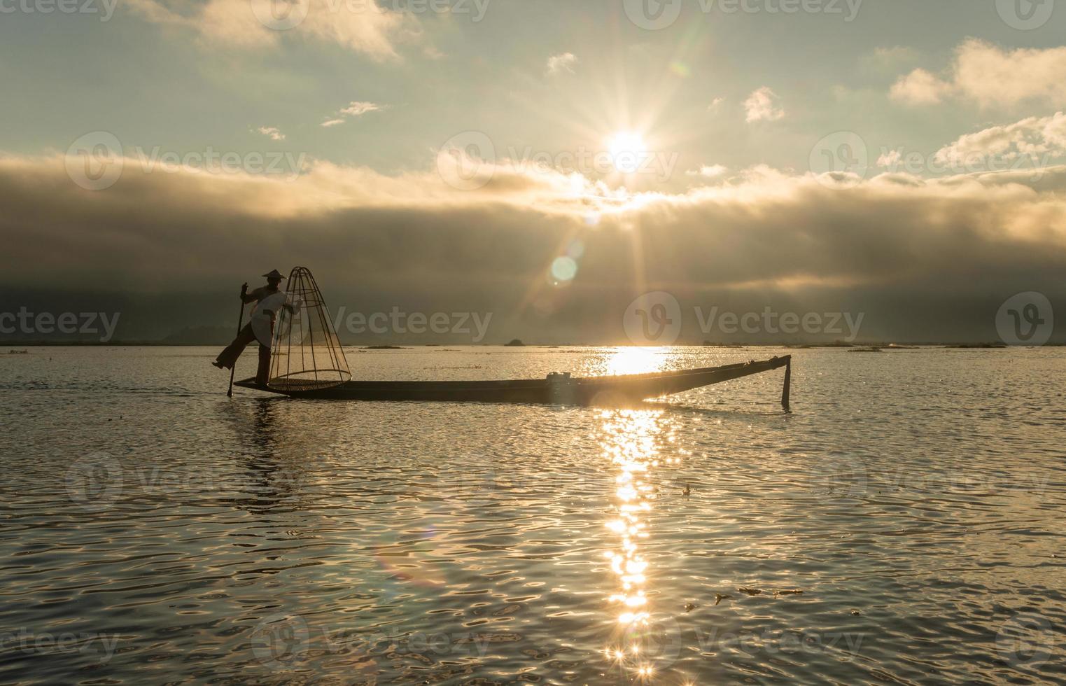 la silueta del pescador intha del lago inle, myanmar. los intha son los únicos en el mundo que pescan con una sola pierna. foto