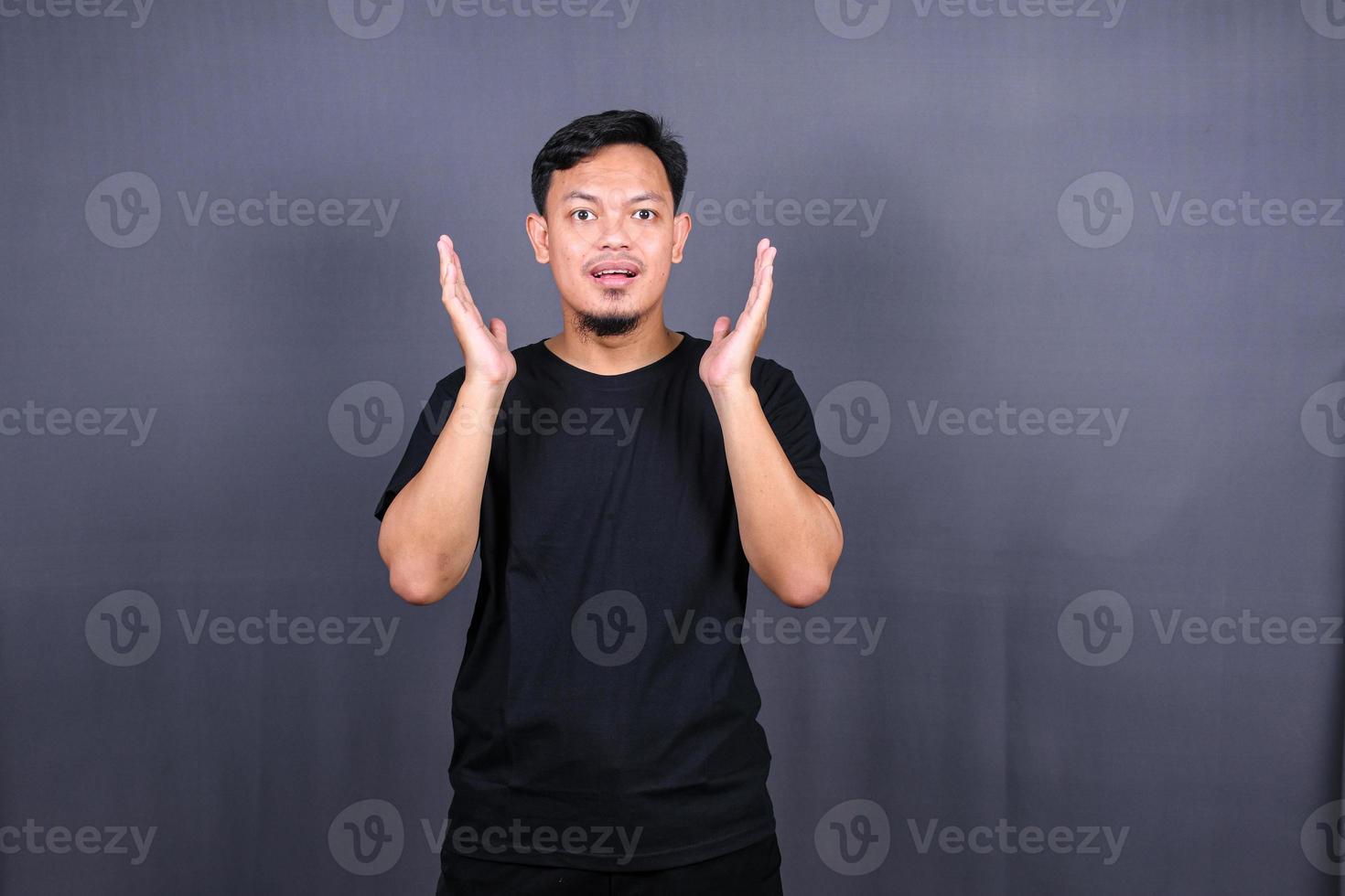 Amazed excited young asian man looking at camera with wow face expression feeling surprised advertising shopping promotion, unbelievable win standing isolated on gray background. photo